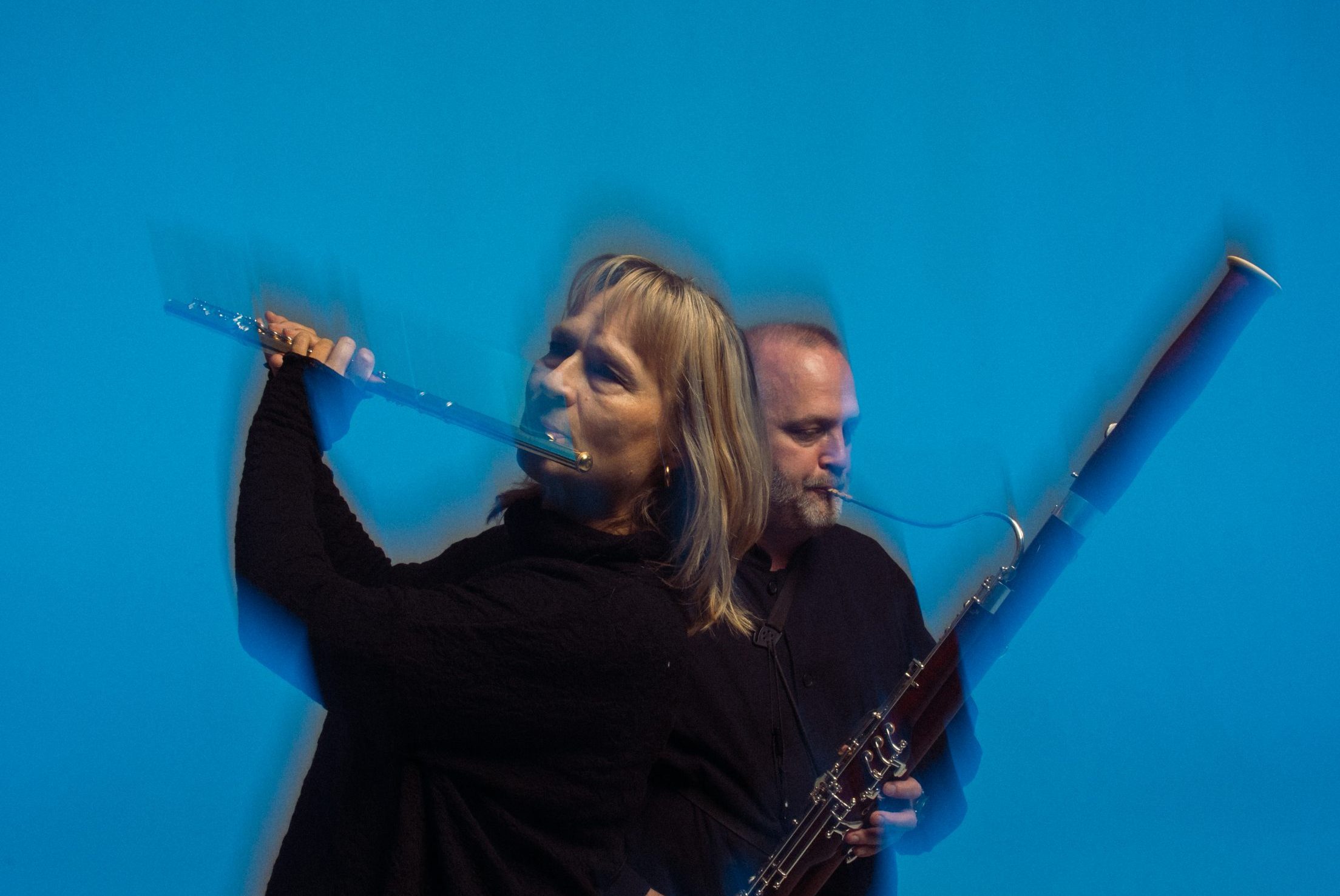 Huilisti etualalla ja fagotisti taka-alalla, sininen tausta.