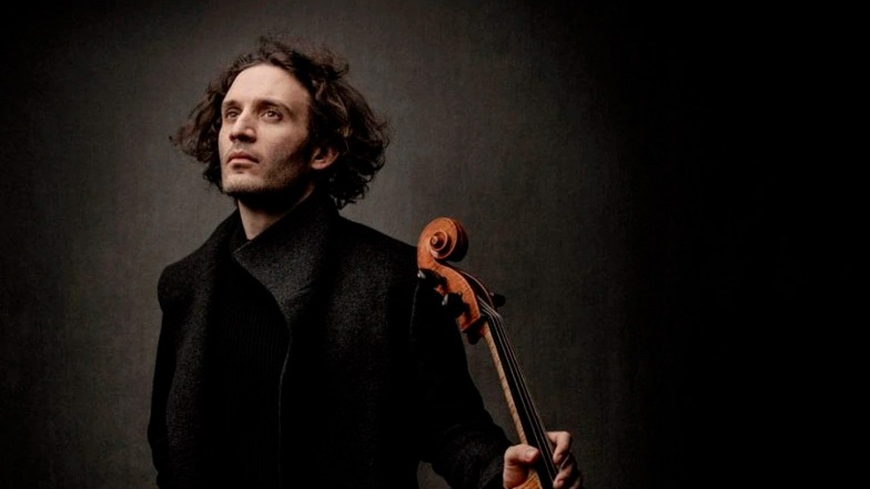 Kiharatukkainen ihminen ja sello mustalla taustalla