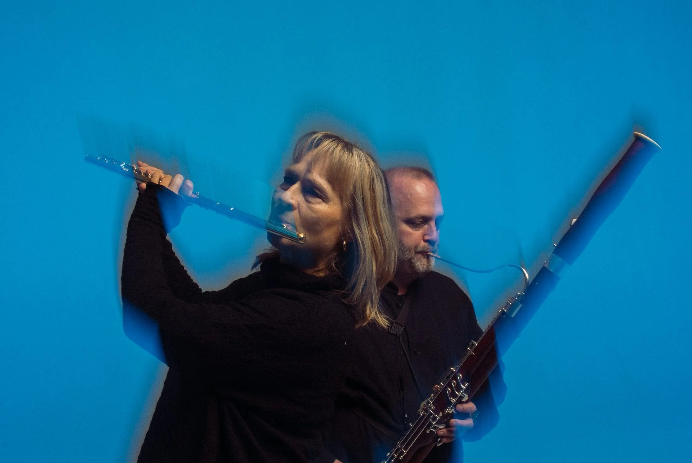 Huilisti etualalla ja fagotisti taka-alalla, sininen tausta.